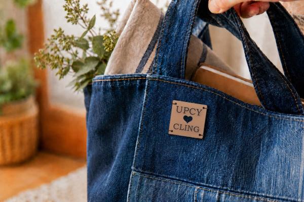 Quadratisches hellbraunes Kaktuslederetikett mit "UPCYCLING" und Herzstanzung auf Jeanstasche.