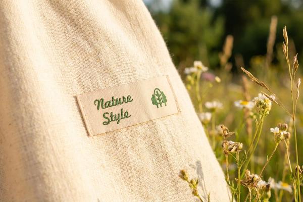 Naturfarbenes Baumwolletikett mit grüner Schrift auf Stoffbeutel