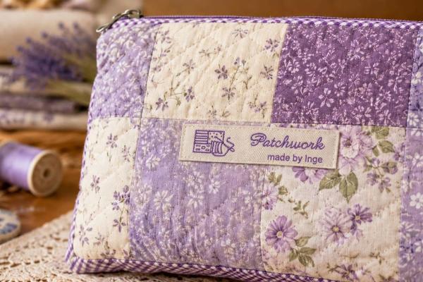 Naturfarbenes Baumwoll-Etikett mit lila Schrift auf Patchwork-Tasche
